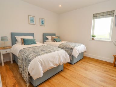 A bedroom with two single beds a nightstand and a window at Pen Bryn in Cyffylliog near Ruthin