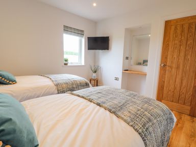 A bedroom with two single beds a window and a wall mounted tv at Pen Bryn in Cyffylliog near Ruthin
