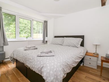 A bedroom with a bed with gray patterned bedding two bedside tables with lamps and a window with gray curtains at Claire Cottage in Gateforth near Hambleton North Yorkshire