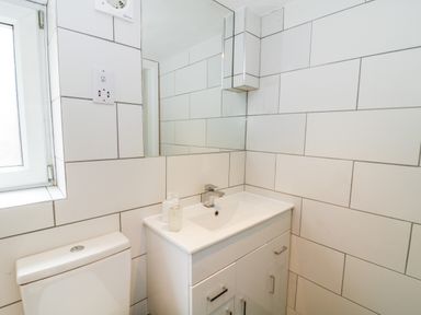 A bathroom with a white sink cabinet a toilet a window and a mirror at Claire Cottage in Gateforth near Hambleton North Yorkshire