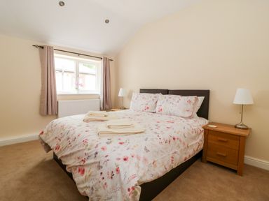 A bedroom with a bed with floral bedding and two bedside tables with lamps at Claire Cottage in Gateforth near Hambleton North Yorkshire