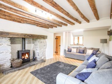 A living room with a fireplace wooden beams on the ceiling two sofas and a rug on the floor at Hafotty Gelynen Maerdy near Corwen