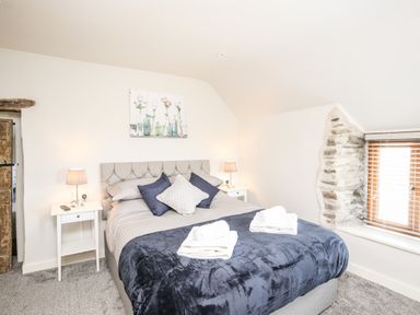 A bedroom with a double bed with folded towels on a blanket and two bedside tables with lamps at Hafotty Gelynen in Maerdy near Corwen