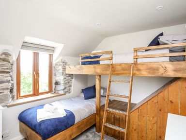 A bedroom with a wooden bunk bed and a window with stone walls at Hafotty Gelynen in Maerdy near Corwen