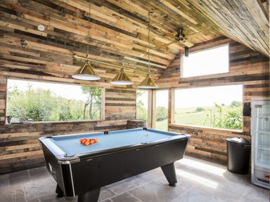 A game room with a pool table and large windows showing outdoor greenery at Hafotty Gelynen in Maerdy near Corwen