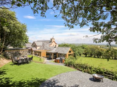A garden with a dining table and chairs near a house with a lawn and gravel area at Hafotty Gelynen in Maerdy near Corwen