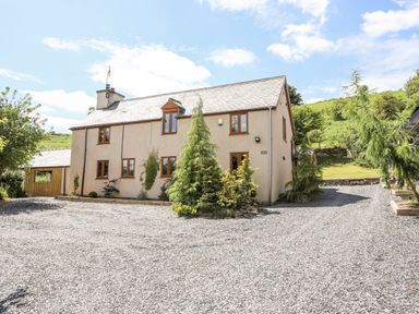 A detached house with gravel driveway and trees at Hafotty Gelynen in Maerdy near Corwen