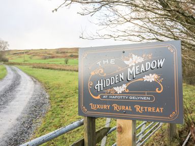 A rural gravel road with a sign for The Hidden Meadow luxury rural retreat at Hafotty Gelynen near Corwen