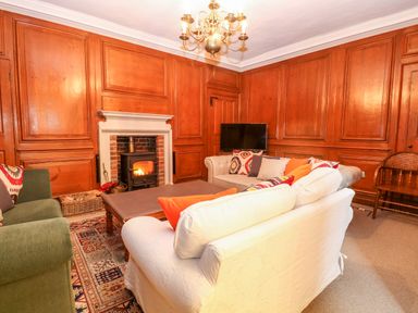 A living room with wooden panel walls fireplace sofas and a chandelier at Enterprise House in Bury St Edmunds