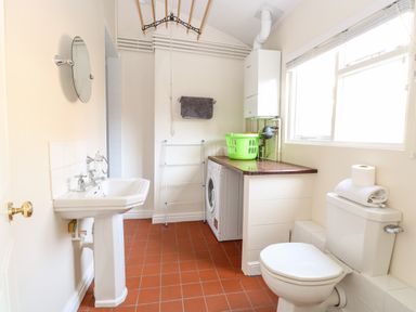 A bathroom with a sink mirror washing machine toilet and window at Enterprise House in Bury St Edmunds