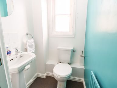 A small bathroom with a toilet sink a towel ring and a window at Enterprise House in Bury St Edmunds