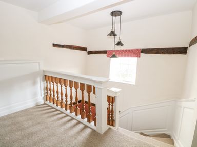 A staircase with wooden banisters and a window with a red patterned curtain at Enterprise House in Bury St Edmunds