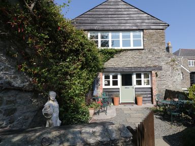 Stone cottage with green door stone patio and garden statues at Crosscombe Barn in Loddiswell