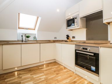 A kitchen with wooden countertops wooden floor and white cabinets at Riviera Heights in Paignton