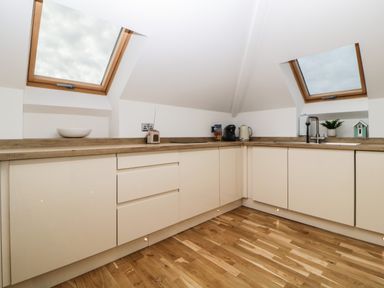 A kitchen with beige cabinets wooden countertops skylight windows and wooden floor at Riviera Heights in Paignton