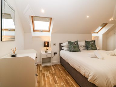 A bedroom with a bed a nightstand with a lamp and a dresser with a mirror at Riviera Heights in Paignton