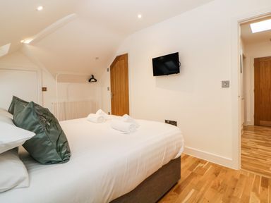 A bedroom with a bed and pillows a wall mounted TV and wooden doors at Riviera Heights in Paignton