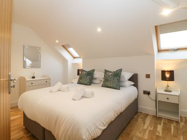 A bedroom with a double bed white linens green pillows bedside tables lamps and wooden flooring at Riviera Heights in Paignton
