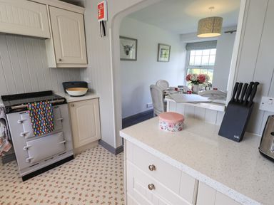 A kitchen with a stove knife block and dining area with table and chairs at Greenstyles in Bowness-On-Windermere