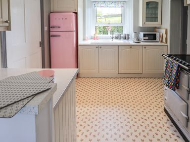 A kitchen with a pink refrigerator a window above the sink and a countertop with a microwave oven at Greenstyles Bowness-On-Windermere