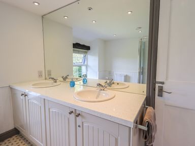 A bathroom with two sinks a large mirror a window and a towel on a rack at Greenstyles in Bowness-On-Windermere