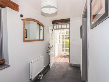 A hallway with a white radiator mirror and open door leading to a glass door at Greenstyles in Bowness-On-Windermere