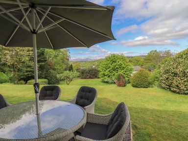 A garden with chairs and a table under an umbrella at Greenstyles in Bowness-On-Windermere