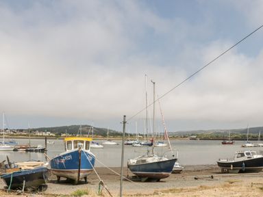 Several boats on the shore and water with hills and buildings in the background at Marlin Cottage in Conwy