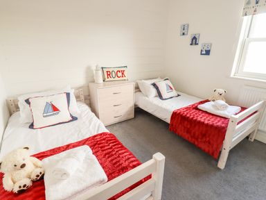 A bedroom with two single beds with red blankets and sailboat pillows at Buck Place The Bay Filey
