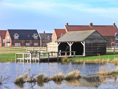 A wooden boathouse and dock on a pond with houses in the background at Buck Place The Bay - Filey