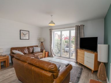 A living room with a sofa and a television at Buck Place The Bay - Filey