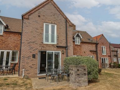 An outdoor area with seating and a brick building at Buck Place The Bay - Filey