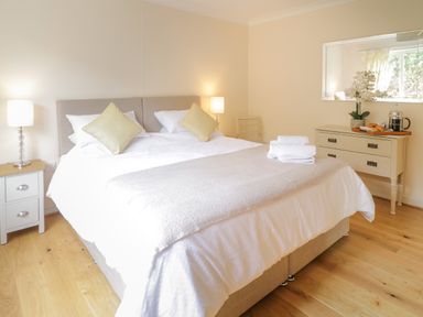 A bedroom with a double bed two bedside tables with lamps a dresser with flowers and breakfast items at Hendre in Penybontfawr