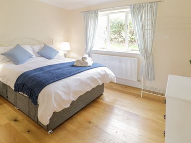 A bedroom with a bed with blue pillows and blanket next to a window with curtains at Hendre Penybontfawr