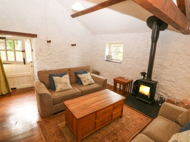 A sitting room with sofas coffee table and wood burning stove at Nant Bach Boduan near Nefyn