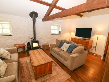 A living room with two sofas a wooden coffee table a wood stove and a television at Nant Bach in Boduan near Nefyn