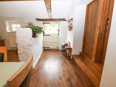 A hallway with wooden floor a white door and a wooden door with steps at Nant Bach in Boduan near Nefyn