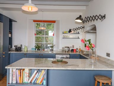 A kitchen with blue cabinets a marble countertop and a bookshelf at Wottonsbury in Ilsington