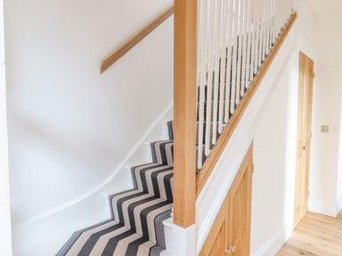 A staircase with striped carpet and wooden handrails in a hallway with wooden doors at Wottonsbury in Ilsington