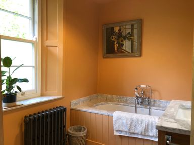 A bathroom with a bathtub towel over the edge radiator and a plant on the windowsill at Wottonsbury in Ilsington