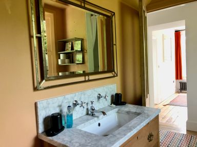 A bathroom sink with a marble countertop and a rectangular mirror above it at Wottonsbury in Ilsington