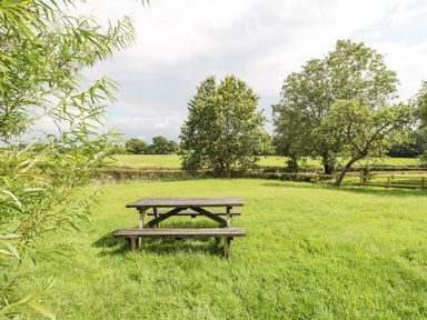 A wooden picnic table on grass with trees and fields in the background at Toms Barn Mudford Sock near Yeovil Somerset