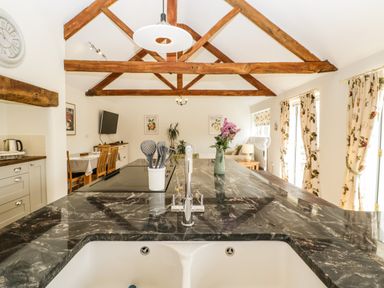 A kitchen with a black marble countertop island and exposed wooden beams at Toms Barn in Mudford Sock near Yeovil Somerset