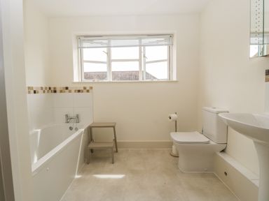 A bathroom with a bathtub a toilet a sink and a window with blinds at Toms Barn in Mudford Sock near Yeovil Somerset