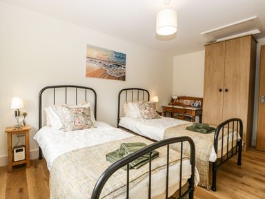 A bedroom with two single beds wooden wardrobe and writing desk at Toms Barn Mudford Sock near Yeovil Somerset