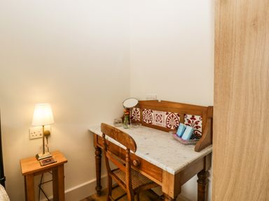 A wooden desk with a marble top next to a wooden chair and a side table with a lamp at Toms Barn in Mudford Sock near Yeovil Somerset