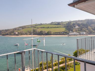 A view of a river with boats and a green hillside with houses seen from a balcony at 32 The Salcombe in Salcombe