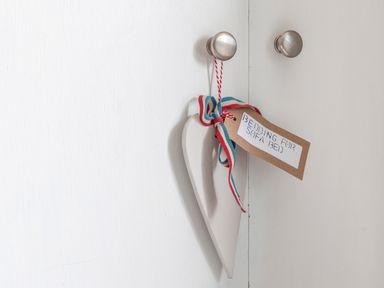 A white heart decoration with a striped ribbon and a label hanging on a cabinet knob at 32 The Salcombe in Salcombe
