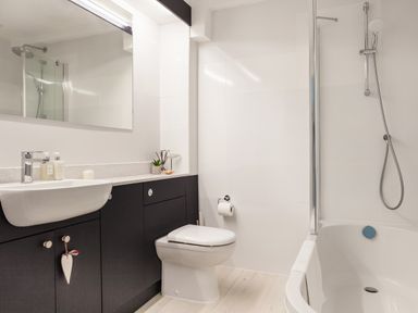A bathroom with a sink cabinet toilet and bathtub with shower at 32 The Salcombe in Salcombe