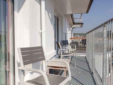 A balcony with three chairs a small table and metal railing at 32 The Salcombe in Salcombe